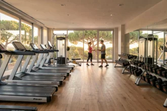 Vue panoramique d'une salle de sport moderne dans le Var avec équipements fitness et fenêtres donnant sur la végétation méditerranéenne